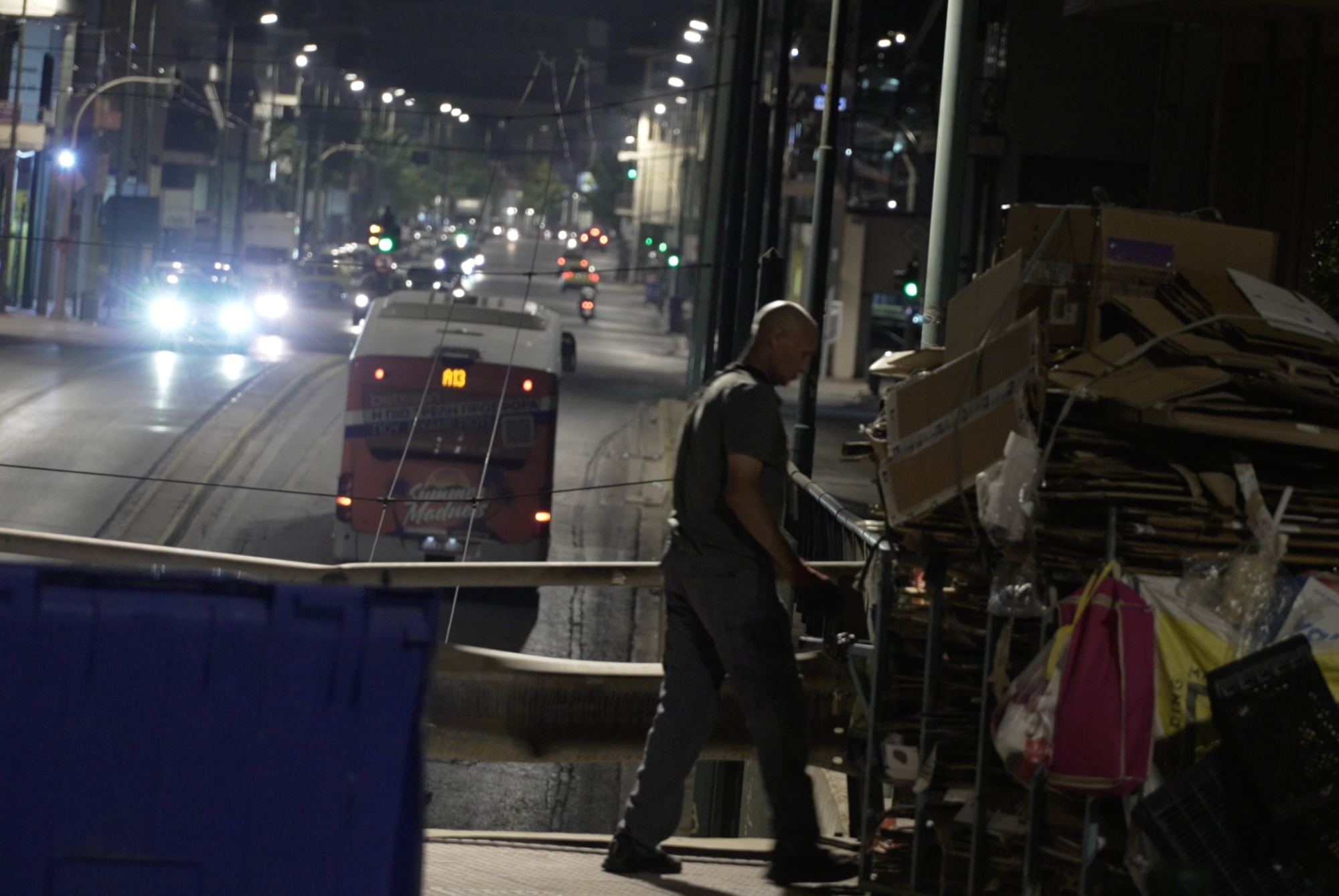 a middle-aged man works in a warehouse at night. in the background there are some vehicles riding on a street 
